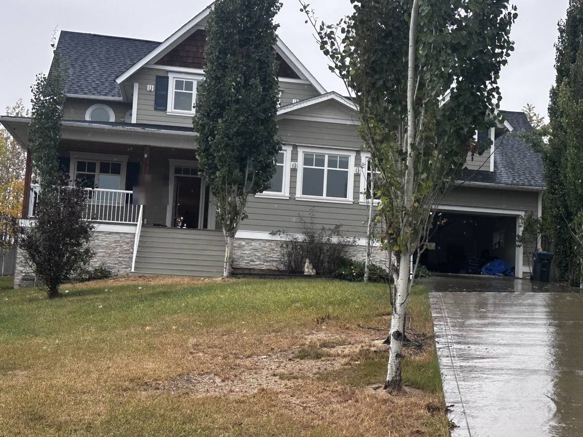 Two-storey house with a covered front porch and an open garage on a rainy October day in Dawson Creek, BC, during a Western Provincial Movers job
