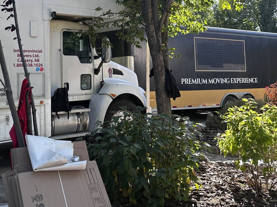 Western Provincial Movers truck and the black and gold Premium Moving Experience trailer parked at the same Lethbridge County home