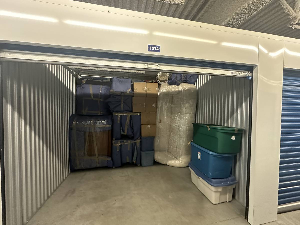 An open storage unit holding blanket-wrapped furniture, cartons and plastic totes on one of our Calgary storage jobs, May 2024