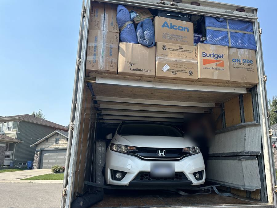 Car on the lower deck of the moving truck under boxes and blanket-wrapped furniture on a Western Provincial Movers job in Evergreen, Calgary, August 2024